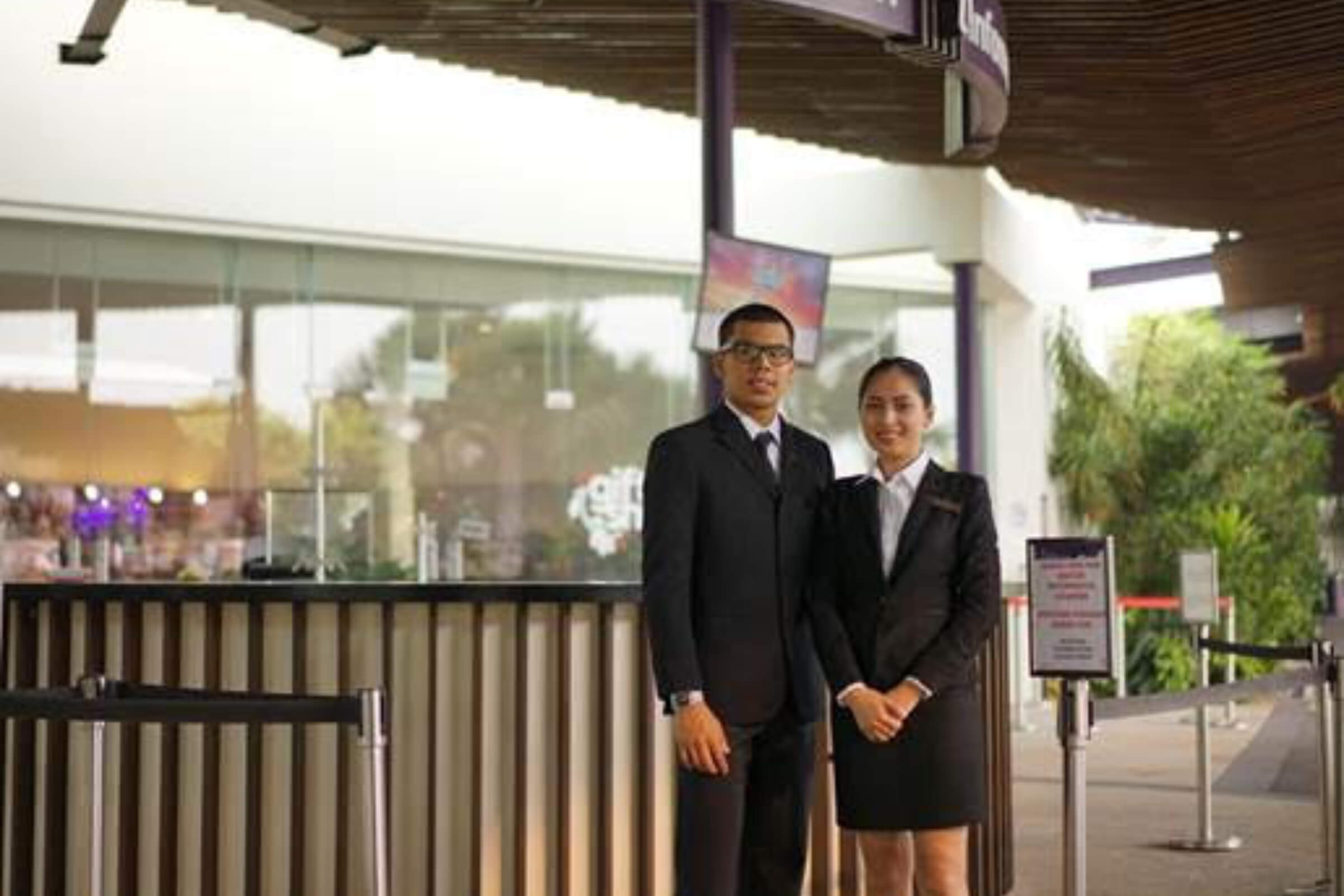 Two professional security personnel standing at an outdoor venue entrance, dressed in formal uniforms, representing Jasa Security Services Singapore